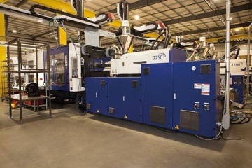 Hala przemysłowa z wtryskarkami do przetwórstwa tworzyw sztucznych Haitian wraz z zamontowanymi robotami z dodatkową klatką bezpieczeństwa.