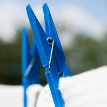 Plastikowe klamerki do prania trzymające białą tkaninę na świeżym powietrzu.