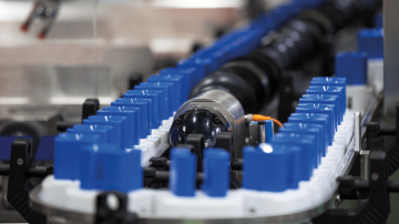 Linia produkcyjna elementów z tworzyw sztucznych transportowanych na przenośniku wokół centralnego wału maszyny, widok z bliska.