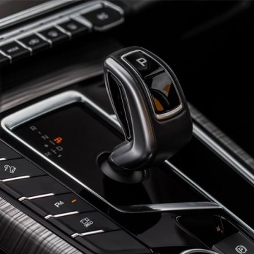Dźwignia automatycznej skrzyni biegów w luksusowym samochodzie, widoczny podświetlany panel oraz przyciski trybów jazdy i parkowania.